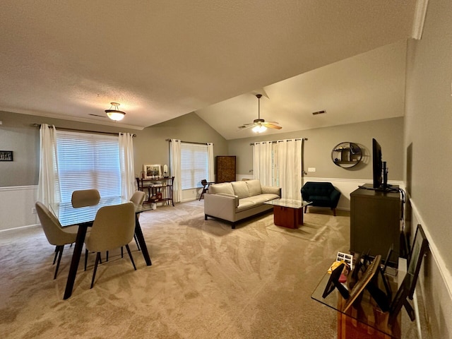 living room with a textured ceiling, light colored carpet, vaulted ceiling, and ceiling fan