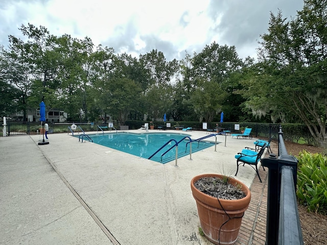 community pool with a patio area and fence