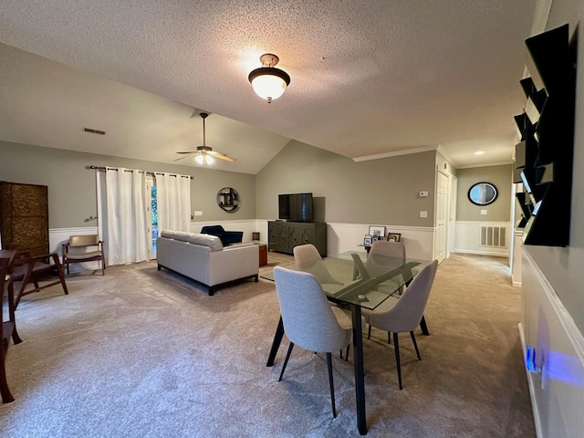 carpeted dining room featuring visible vents, vaulted ceiling, a textured ceiling, and ceiling fan