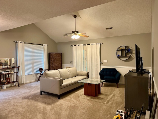 living room featuring lofted ceiling, a textured ceiling, light colored carpet, visible vents, and a ceiling fan