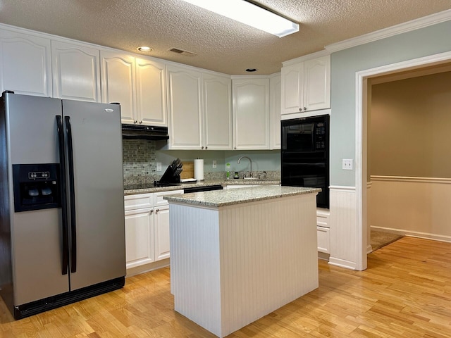 kitchen featuring black appliances, light stone counters, white cabinetry, and under cabinet range hood