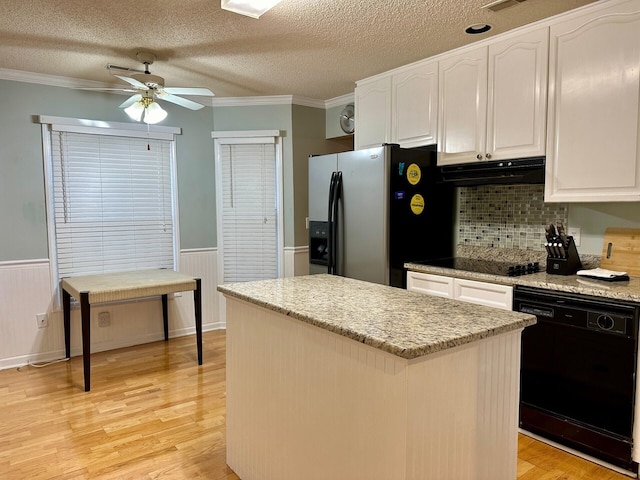 kitchen featuring a center island, wainscoting, black appliances, and extractor fan