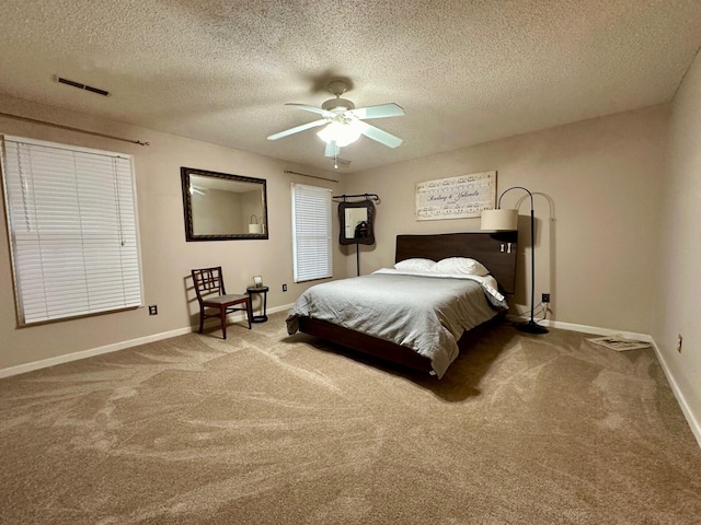 carpeted bedroom with visible vents, a textured ceiling, and baseboards