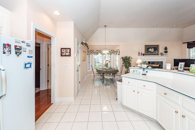 kitchen featuring hanging light fixtures, light tile patterned floors, white cabinetry, a fireplace, and white fridge