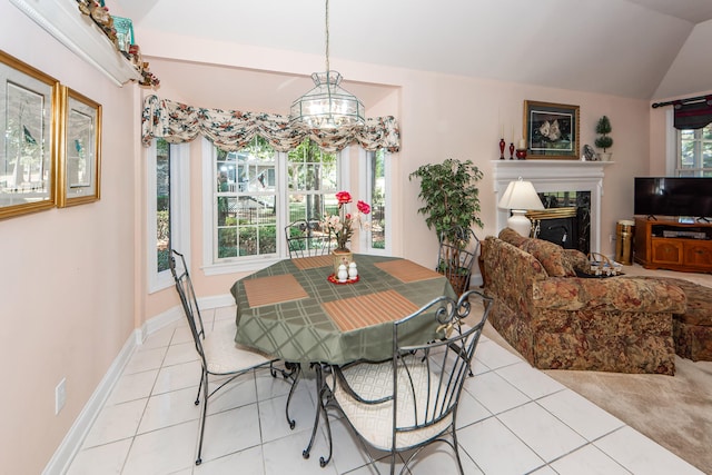 tiled dining area with a premium fireplace, lofted ceiling, and a chandelier