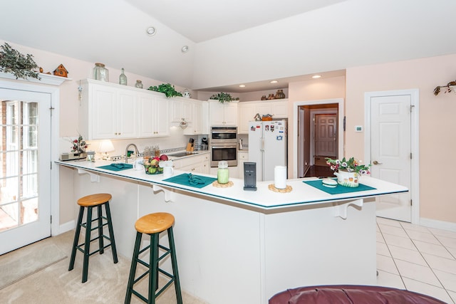 kitchen featuring a kitchen breakfast bar, kitchen peninsula, white cabinetry, and white fridge