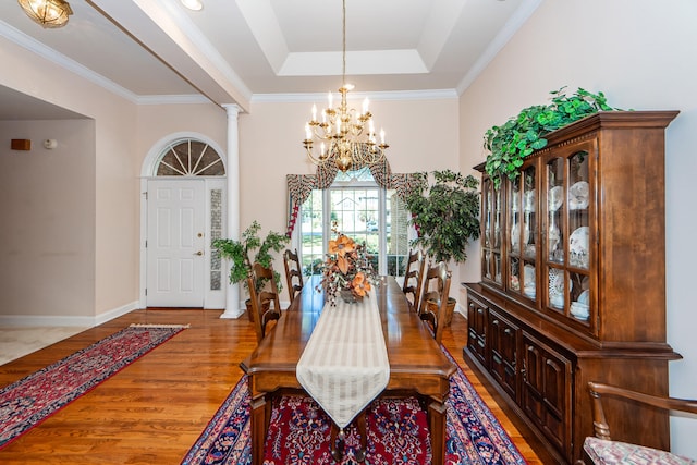 foyer entrance featuring ornamental molding, hardwood / wood-style floors, a tray ceiling, and decorative columns