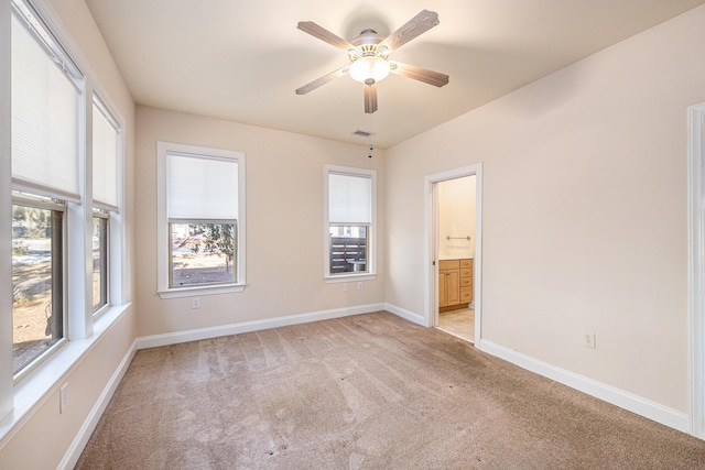 unfurnished bedroom with baseboards, visible vents, ensuite bath, and light colored carpet