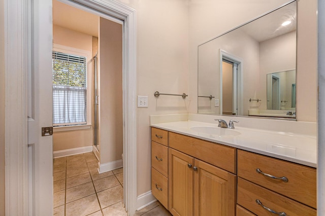 full bath featuring tile patterned floors, vanity, a shower stall, and baseboards