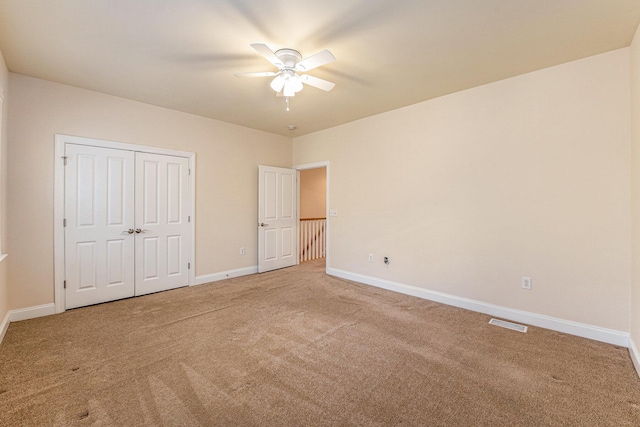 unfurnished bedroom with visible vents, a closet, baseboards, light carpet, and a ceiling fan