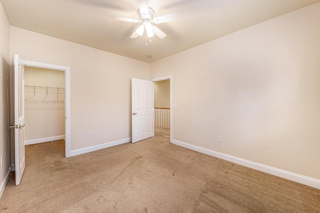 unfurnished bedroom with a closet, a spacious closet, baseboards, and light carpet