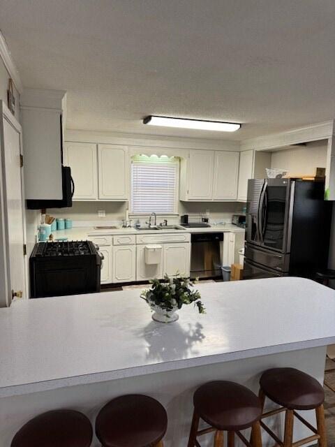 1188 Blackberry Bush Rd, Summerton, SC 29148 - kitchen with a kitchen bar, light countertops, a sink, white cabinets, and black appliances