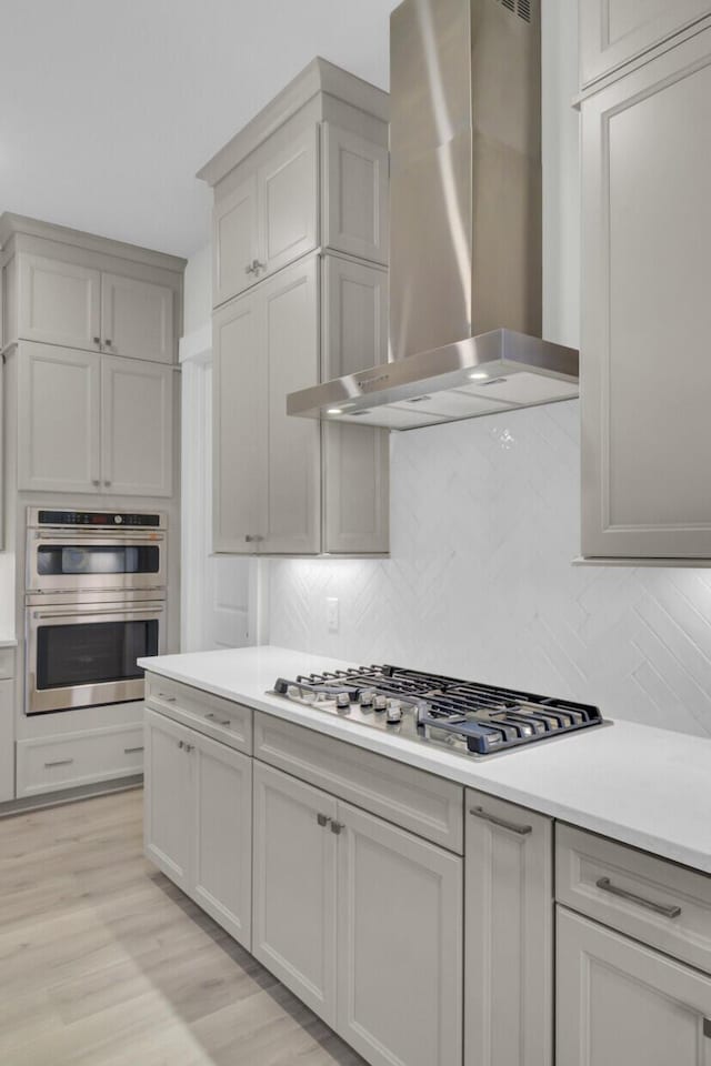 3029 Robeson Trce, Johns Island, SC 29455 - kitchen featuring wall chimney exhaust hood, stainless steel appliances, tasteful backsplash, light countertops, and light wood-type flooring