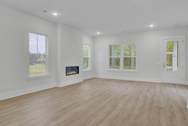 3029 Robeson Trce, Johns Island, SC 29455 - unfurnished living room featuring light wood finished floors, plenty of natural light, a glass covered fireplace, and recessed lighting