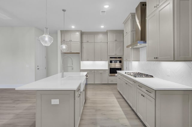 3029 Robeson Trce, Johns Island, SC 29455 - kitchen featuring wall chimney range hood, stainless steel appliances, light wood finished floors, tasteful backsplash, and recessed lighting