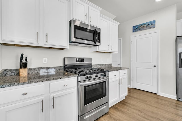 9706 Fanning Basket Ln, Ladson, SC 29456 - kitchen with appliances with stainless steel finishes, white cabinetry, baseboards, dark stone counters, and light wood-style flooring