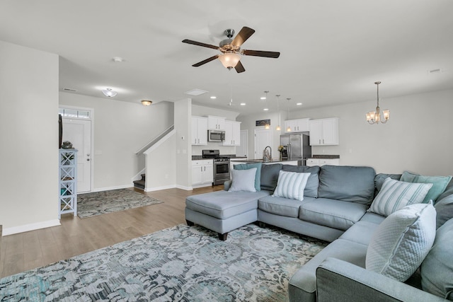 9706 Fanning Basket Ln, Ladson, SC 29456 - living area featuring stairs, baseboards, wood finished floors, and ceiling fan with notable chandelier