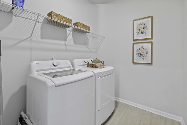 clothes washing area featuring laundry area, baseboards, and washer and dryer