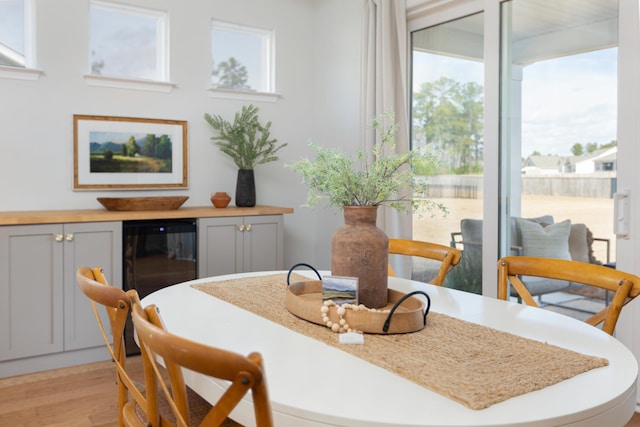 dining room with wine cooler, a fireplace, and light wood-style flooring