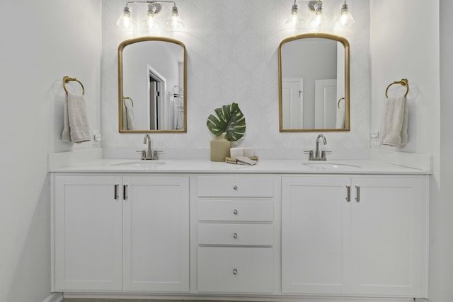 full bath featuring double vanity, wallpapered walls, and a sink