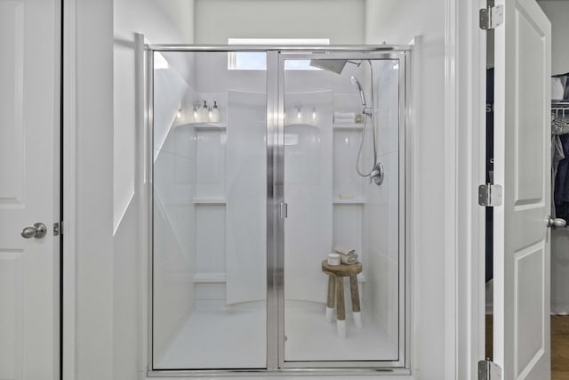 bathroom featuring a spacious closet and a shower stall