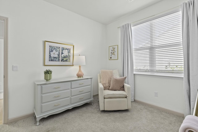 living area featuring light carpet and baseboards