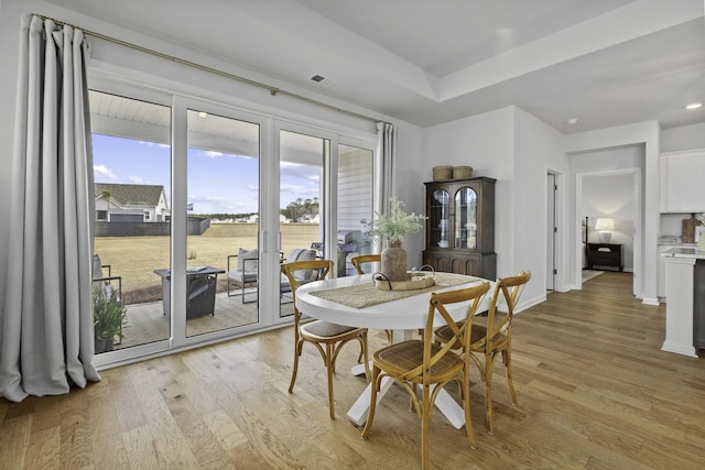 dining area featuring light wood-style flooring, visible vents, and baseboards