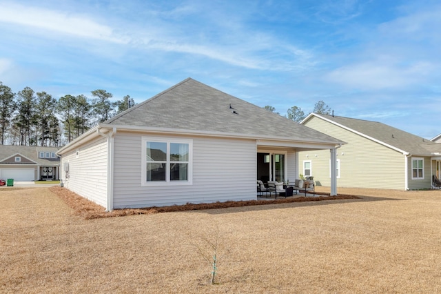 back of house with roof with shingles and a patio