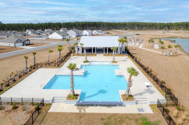 community pool with a residential view, fence, and a patio