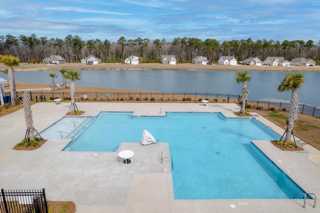 community pool featuring a patio area, a water view, and fence