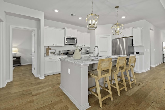 kitchen featuring stainless steel appliances, visible vents, light wood finished floors, and white cabinetry