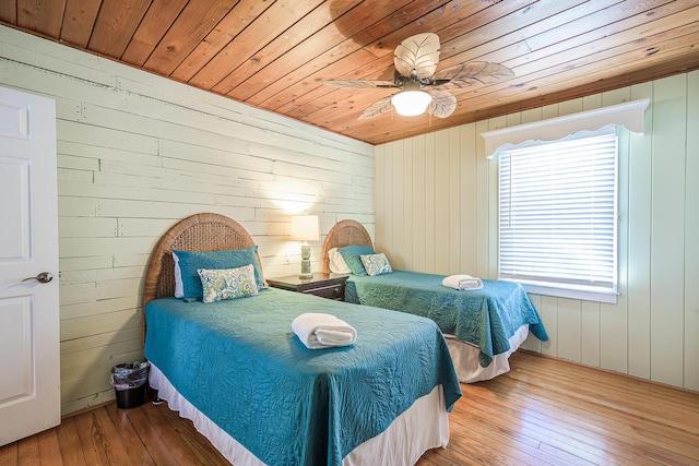 bedroom with wooden walls, hardwood / wood-style flooring, ceiling fan, and wooden ceiling