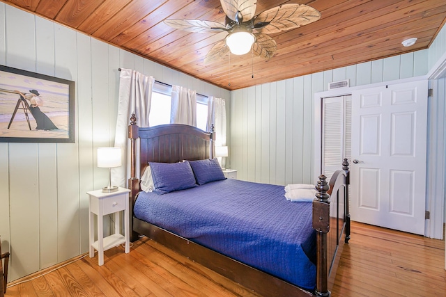 bedroom with ceiling fan, wood walls, light wood-type flooring, and wood ceiling