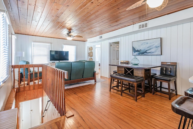 living room with plenty of natural light, wood ceiling, wooden walls, and light hardwood / wood-style flooring