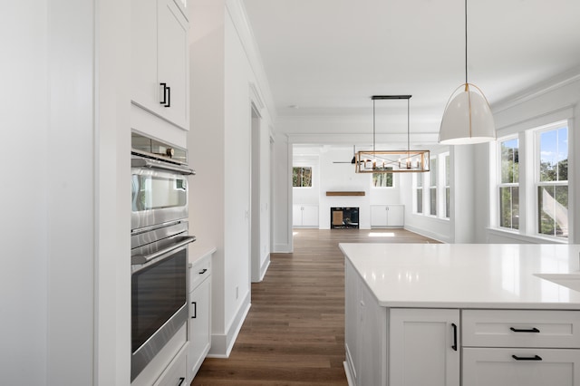 kitchen featuring white cabinets, hanging light fixtures, dark hardwood / wood-style floors, ornamental molding, and double oven