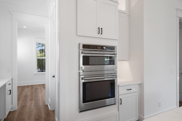 kitchen featuring dark hardwood / wood-style flooring, white cabinets, and stainless steel double oven