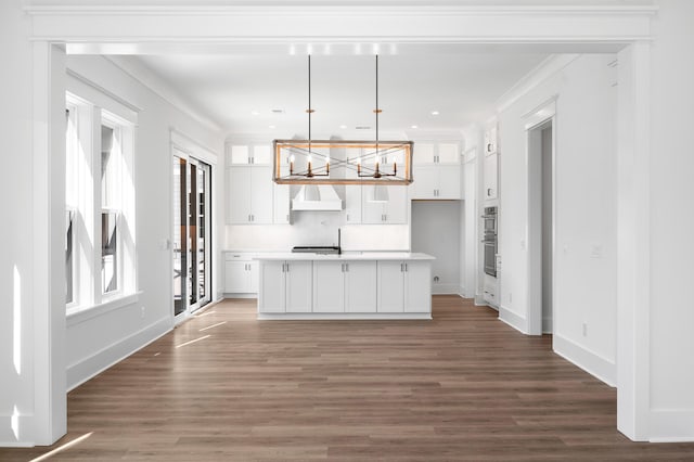 kitchen with decorative light fixtures, dark hardwood / wood-style floors, premium range hood, and a kitchen island with sink