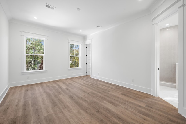 empty room with hardwood / wood-style floors and ornamental molding