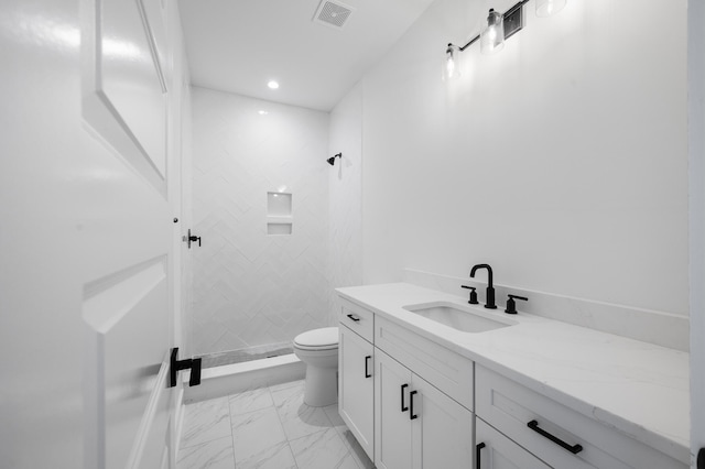 bathroom with toilet, vanity, and tiled shower