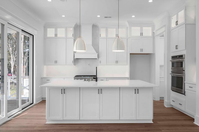 kitchen with white cabinets, custom range hood, and a kitchen island with sink