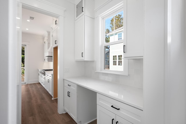 kitchen with white cabinets, built in desk, and dark wood-type flooring