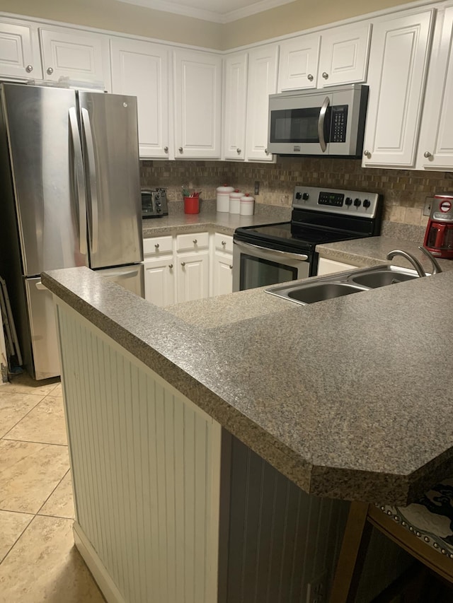 kitchen featuring kitchen peninsula, appliances with stainless steel finishes, sink, light tile patterned floors, and white cabinetry