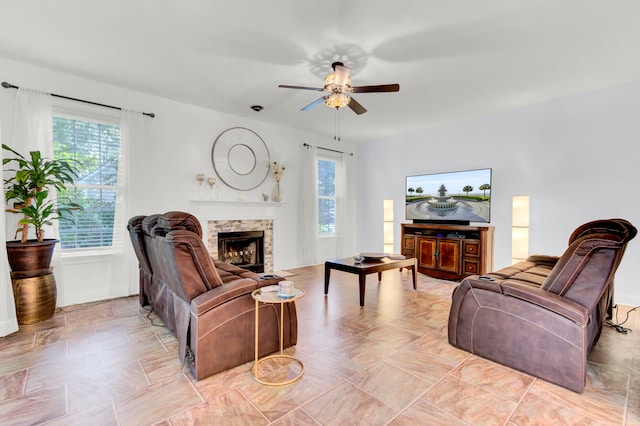 living room featuring ceiling fan, a fireplace, a wealth of natural light, and light tile patterned floors