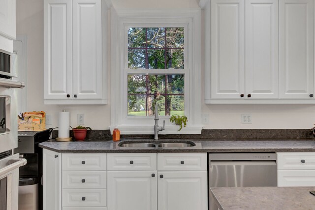 kitchen with a healthy amount of sunlight, stainless steel dishwasher, and white cabinetry