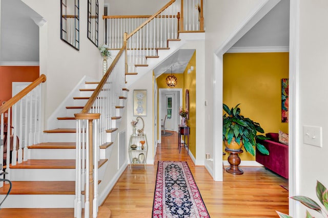 foyer with crown molding and light hardwood / wood-style floors