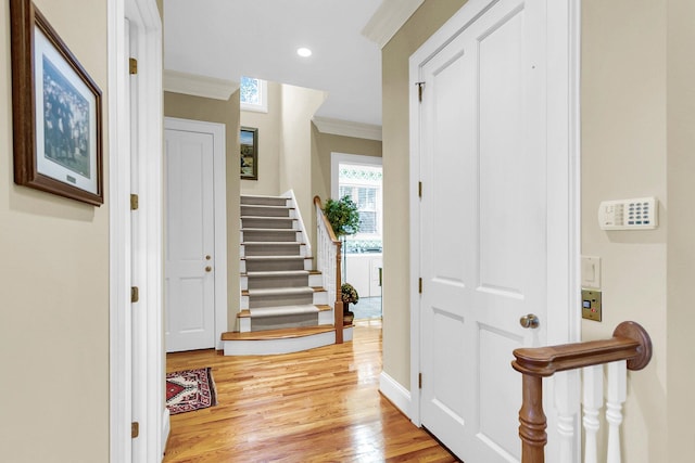 foyer with light wood-type flooring and crown molding