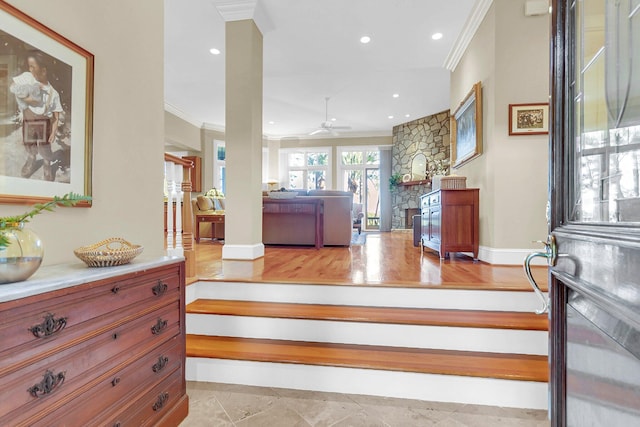 stairway with ornamental molding, wood-type flooring, ceiling fan, and a stone fireplace