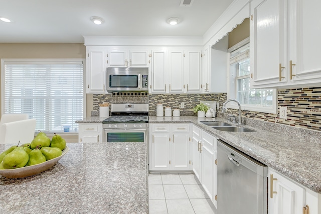 kitchen with sink, appliances with stainless steel finishes, white cabinets, and decorative backsplash