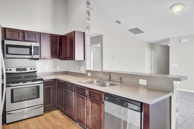 kitchen featuring kitchen peninsula, light wood-type flooring, appliances with stainless steel finishes, and sink