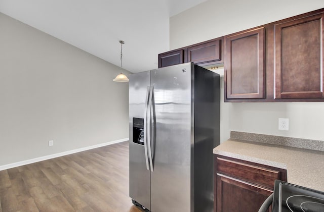 kitchen featuring wood-type flooring, stainless steel fridge, vaulted ceiling, and hanging light fixtures